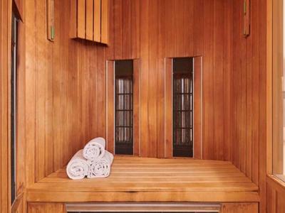 Interno di una sauna con pareti in legno e tre asciugamani piegati sulla panca.