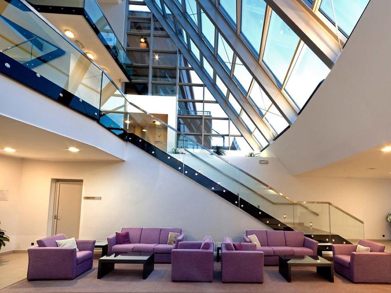 Lobby moderna con divani viola e grande finestra a soffitto in vetro