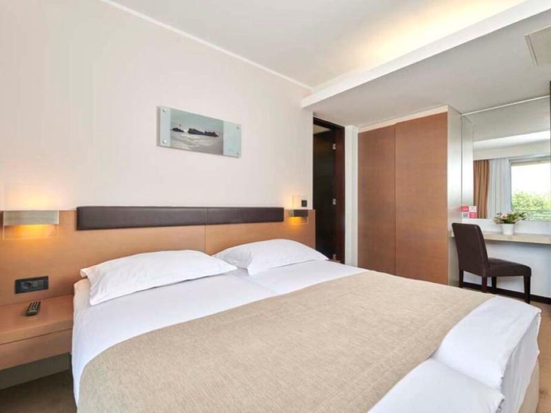 Camera d'hotel moderna con letto matrimoniale, mobili in legno e scrivania vicino alla finestra.