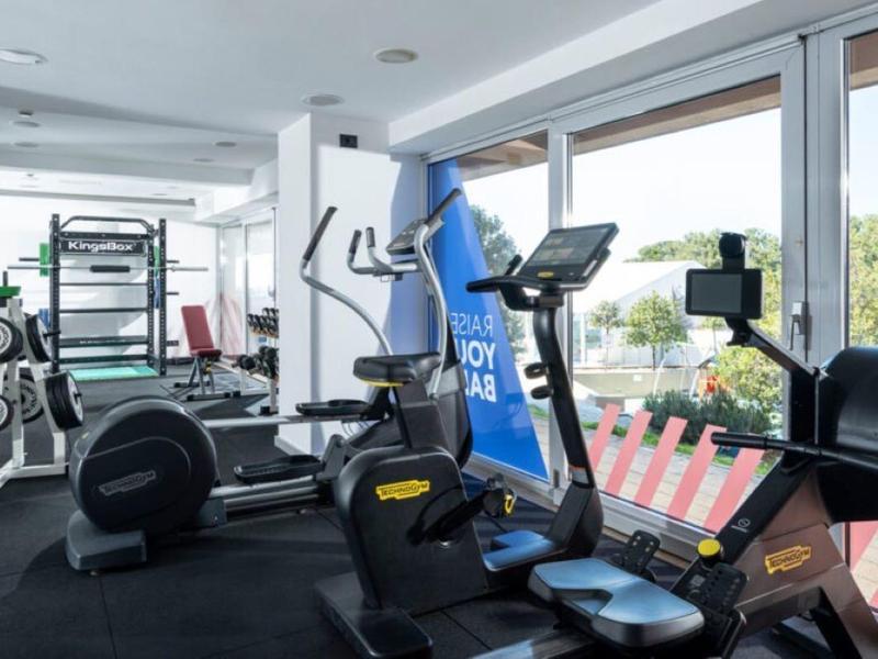 Palestra moderna con attrezzature per l'allenamento e grandi finestre con vista esterna.