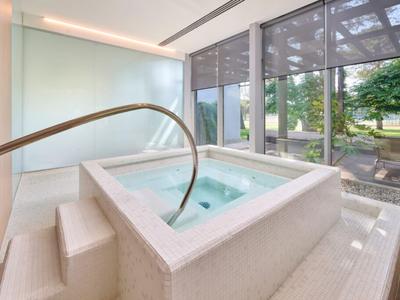Interior with modern hot tub, large windows, and a view of green areas.