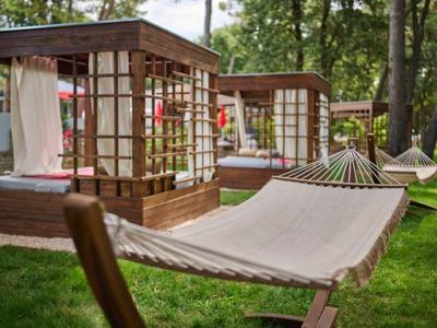 White hammock on green grass in front of garden pavilions at a hotel.