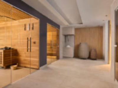 Modern, bright hotel room with wood decor, seating area, and large mirror.