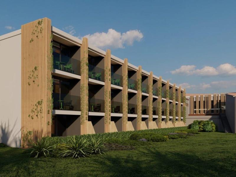 Moderní hotelový komplex s balkónovými pokoji a upraveným trávníkem vpředu.