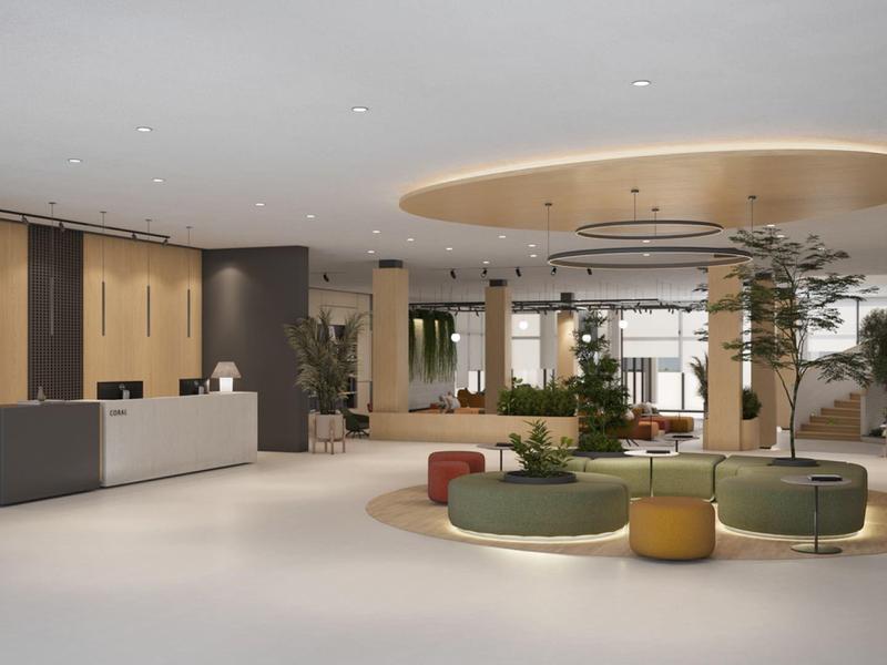Moderní hotelová recepce se světlým interiérem, recepčním pultem a kulatými sedacími plochami.