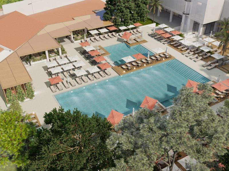 Letecký pohled na luxusní hotelový bazén s lehátky a slunečníky.