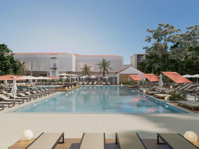 Velký venkovní bazén s lehátky a slunečníky vedle hotelové budovy.