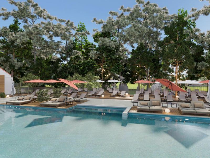 Velký venkovní bazén se slunečníky a lehátky před stromy