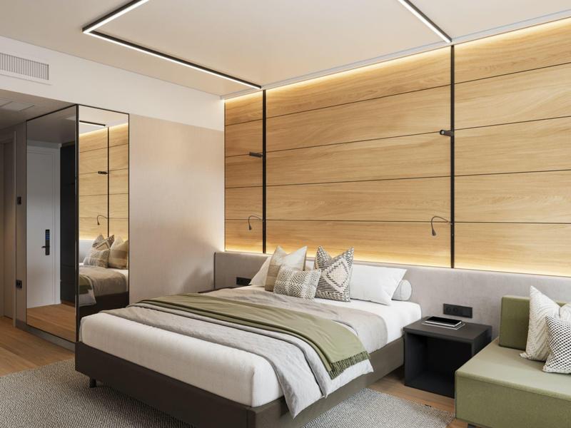 Moderní hotelový pokoj s velkou postelí, dřevěnou zdí a útulným posezením.