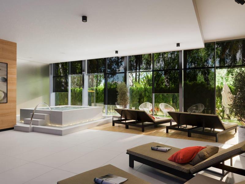 Moderní wellness prostor s vířivkou, lehátky a velkými okny s výhledem do zeleně.