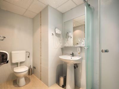 Helles, sauberes Hotelbadezimmer mit Toilette, Waschbecken, Spiegel und Duschkabine.