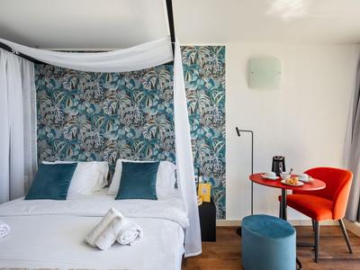 Modernes Schlafzimmer mit Himmelbett, buntem Blumenakzent und gemütlichem Sitzbereich.