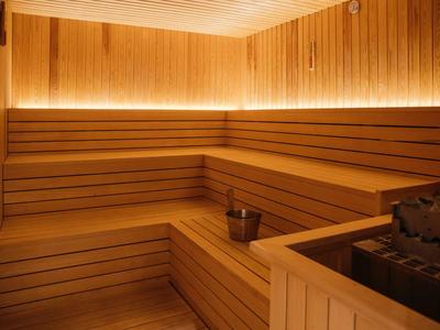 Innensauna mit hölzernen Sitzbänken, Wandelementen und Saunaofen mit Wassereimer.