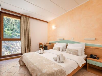 Gemütliches Hotelzimmer mit Doppelbett, großem Fenster und mediterraner Wandfarbe.