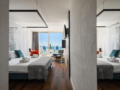 Modernes Hotelzimmer mit Doppelbett, Meerblick und Balkon mit Sitzbereich