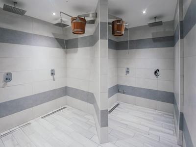 Moderner Duschbereich mit Regenduschen und Holzeimer-Duschköpfen in einem Hotelbad.