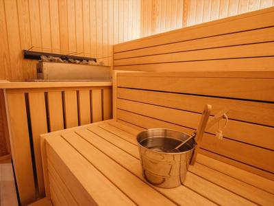 Innensauna aus Holz mit Holzbänken und einem Metalleimer mit Kelle.