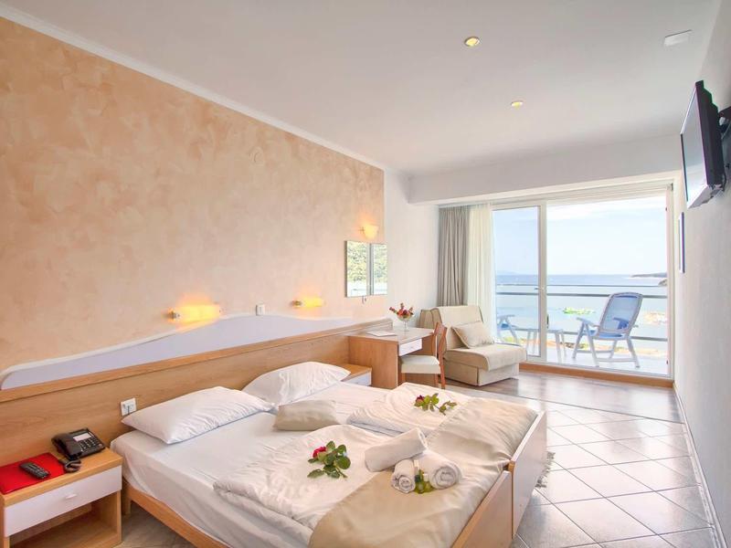 Bright hotel room with double bed, balcony, and sea view.