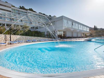 Piscina redonda al aire libre junto a un edificio de hotel moderno bajo un cielo despejado.