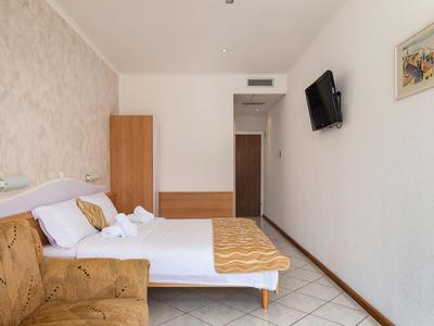 Habitación de hotel moderna con cama doble, sofá, televisor en la pared y decoración sencilla.