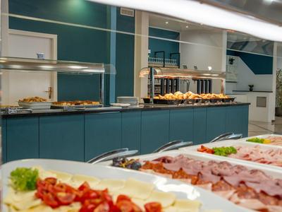 Bufet con diversos embutidos y quesos en una moderna sala de desayuno.