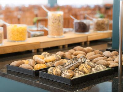 Varios tipos de pan en cestas con pinzas en un área de buffet.