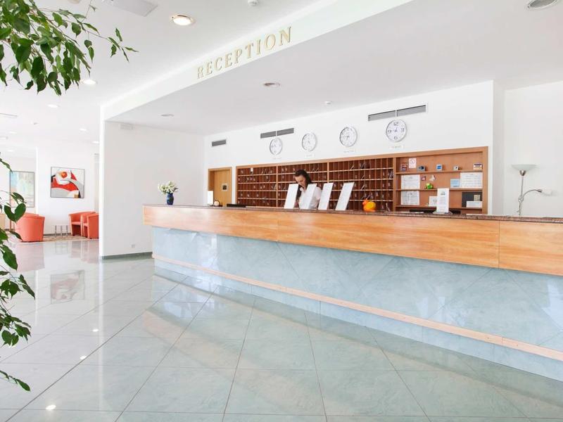 Bright hotel lobby reception area with wooden counter and white decor.