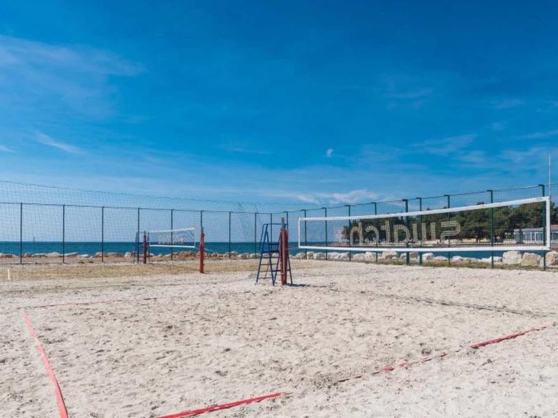 Sand volleyball court on the beach with a view of the sea under a blue sky.