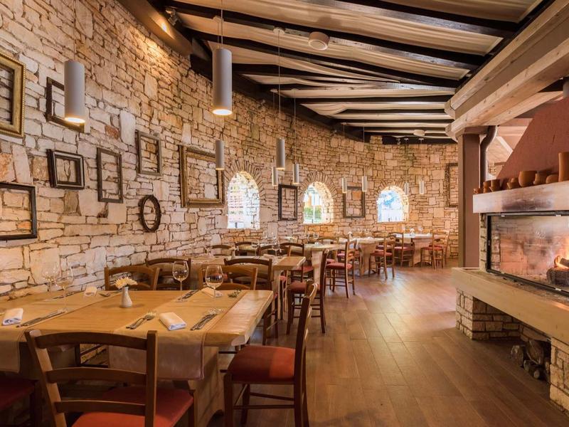 Cozy restaurant with stone walls, wooden beam ceiling, and fireplace fire.