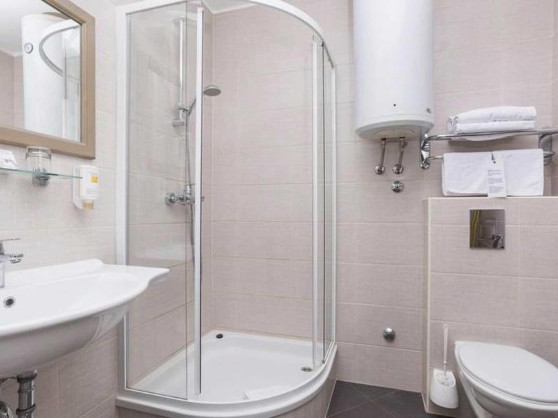 Small bathroom with shower enclosure, sink, and toilet in neutral colors.