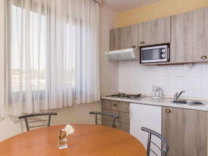 Small kitchen with wooden table, metal chairs, curtains, and modern built-in appliances.