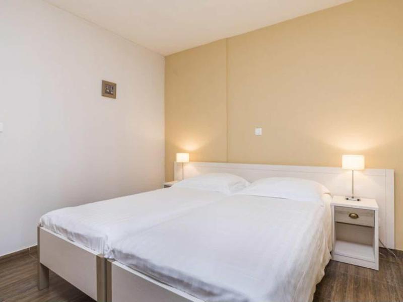 Simple hotel room with large double bed, white walls, and bedside tables with lamps.