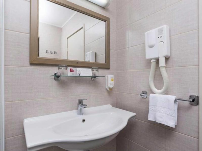 Modern bathroom with sink, large mirror, and wall-mounted towel holder.