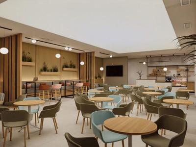 Moderner, heller Hotel-Loungebereich mit Tischen, Stühlen und Barbereich im Hintergrund.