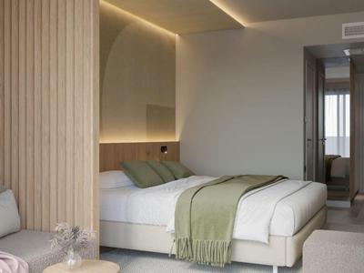 Habitación de hotel moderna con cama doble, manta verde y detalles de madera.