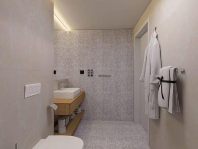 Baño de hotel moderno con paredes grises, lavamanos y toallas colgadas en la pared.