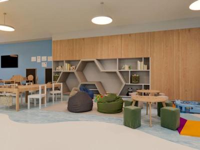 Sala luminosa de juego y aprendizaje con muebles de madera, pufs y juguetes.