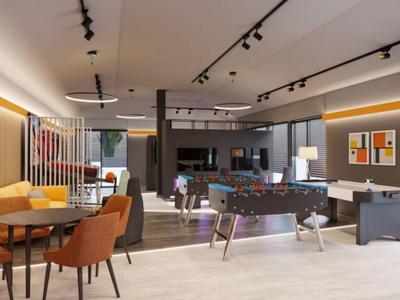 Área de salón moderna de hotel con asientos, mesa de futbolín y decoración contemporánea.