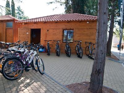 Meerdere fietsen staan op een geplaveid plein voor een houten gebouw met een rood dak.