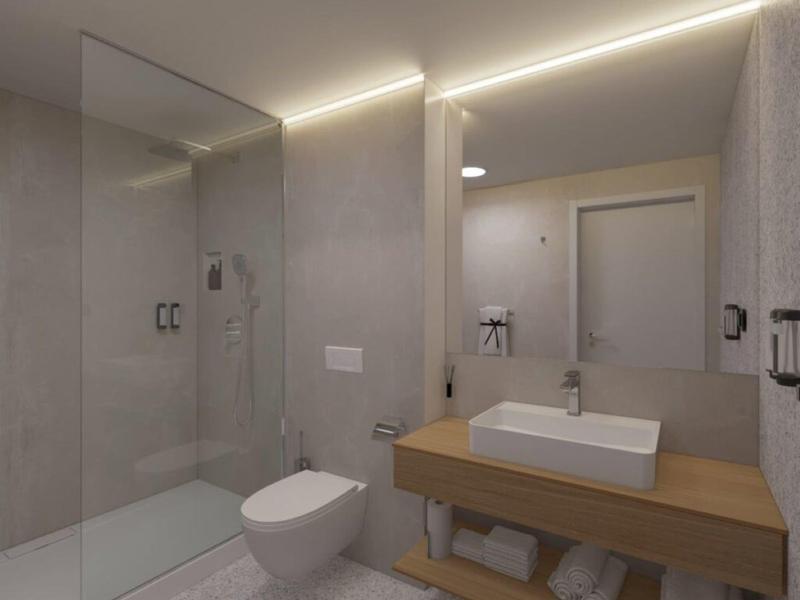 Baño moderno con ducha a nivel, inodoro y mueble de lavabo de madera con toallas.