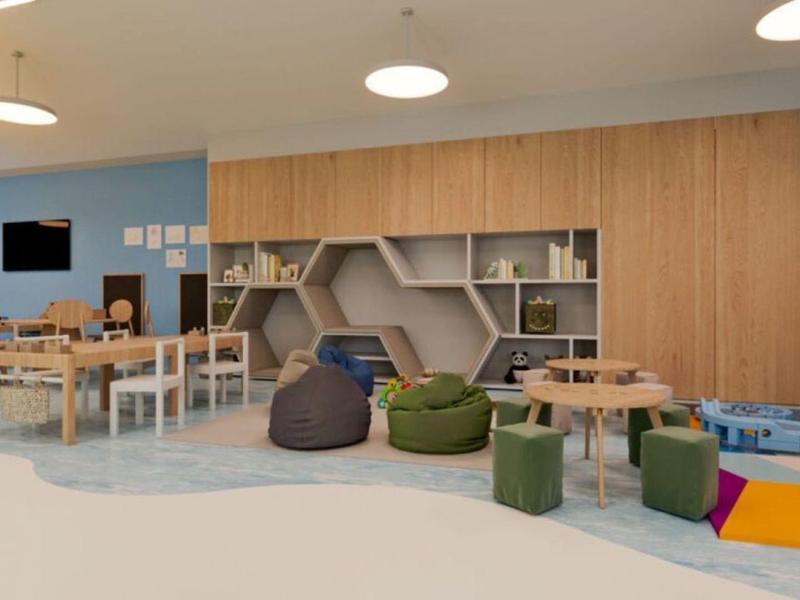 Sala luminosa de juego y aprendizaje con muebles de madera, pufs y juguetes.