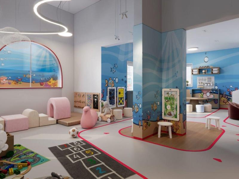 Área de juegos moderna con asientos, juguetes y vista al mar en un hotel.