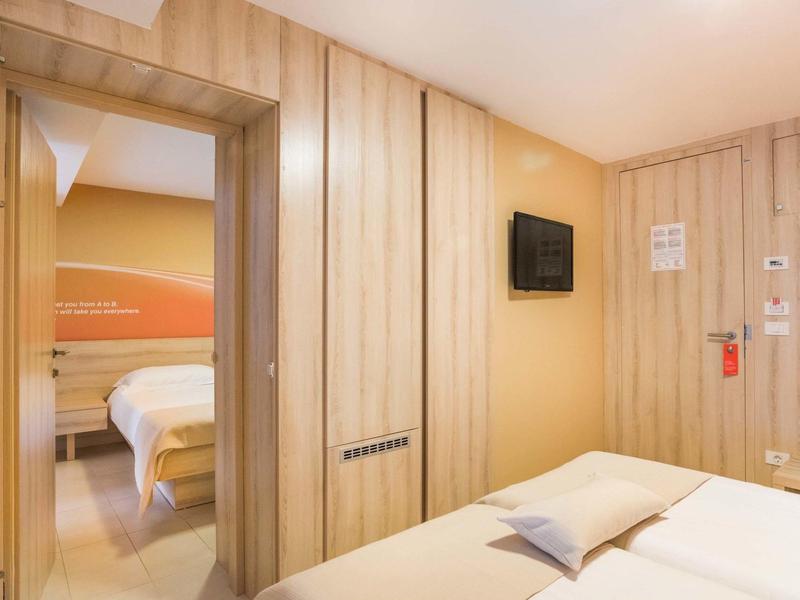 Nowoczesny pokój hotelowy z drewnianymi ścianami, łóżkiem podwójnym i widokiem na przyległy pokój.