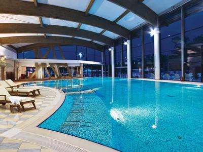 Modern overdekt zwembad met ligstoelen en panoramische ramen 's nachts