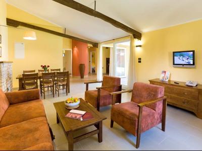 Gezellige woonkamer met rode fauteuils, bruine bank, houten meubels en gele muren.