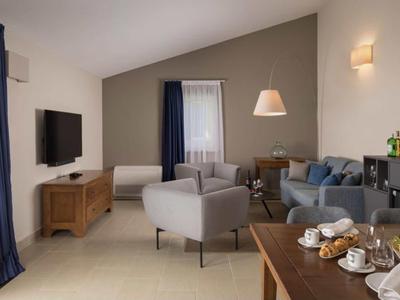 Moderne woonkamer met bank, fauteuils, tv en gedekte ontbijttafel.