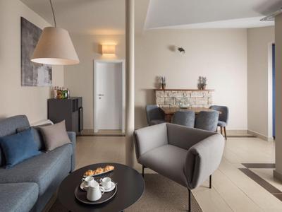 Modern eingerichteter Hotel-Warteraum mit grauem Sofa, Sesseln und rundem schwarzen Tisch.