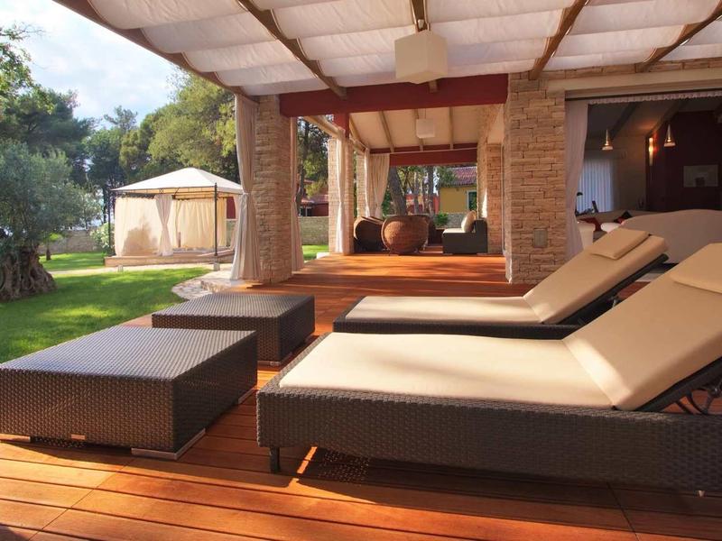 Moderne veranda met ligstoelen met uitzicht op tuin en tent op vakantieplek.