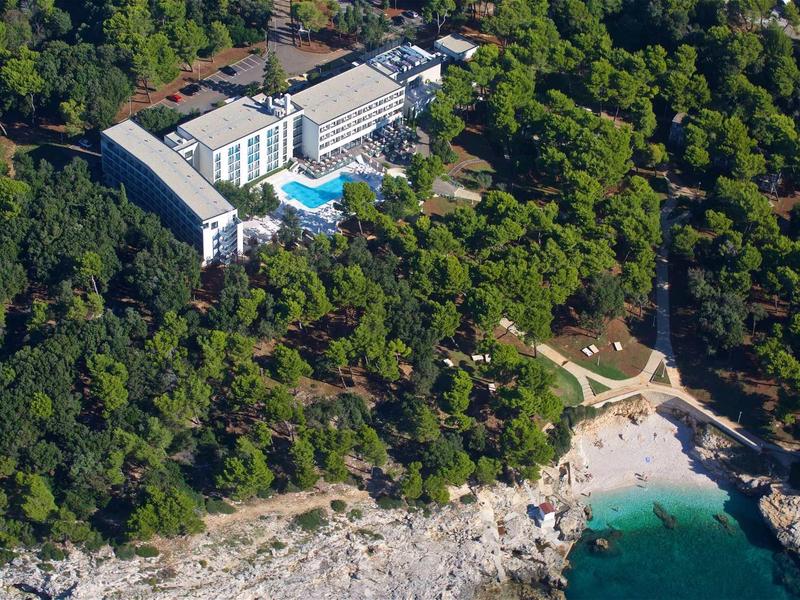 Luksusowy hotel z basenem otoczony gęstym lasem przy wybrzeżu z plażą i czystą wodą.