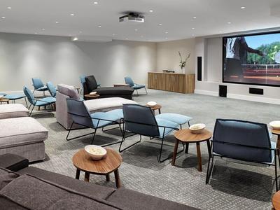 Moderní konferenční místnost s posezením a velkou obrazovkou pro prezentace.